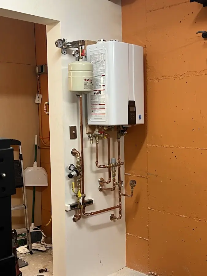 Plumbing technician inspecting water heater connections in Wellsboro